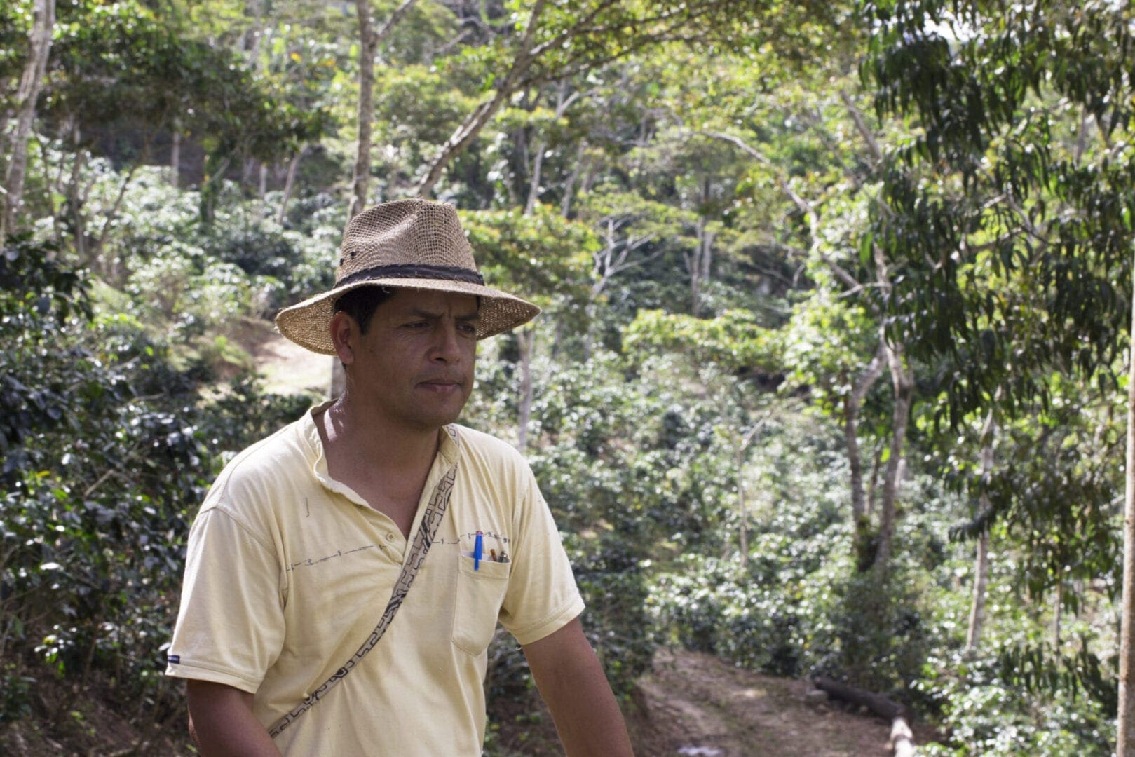 A man in a hat standing on the side of a river.